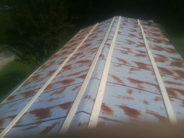 Rusted metal roof panels with new wood purlins before replacement — Storm Damage Roof Repair in Keithsburg by Roofing Brothers