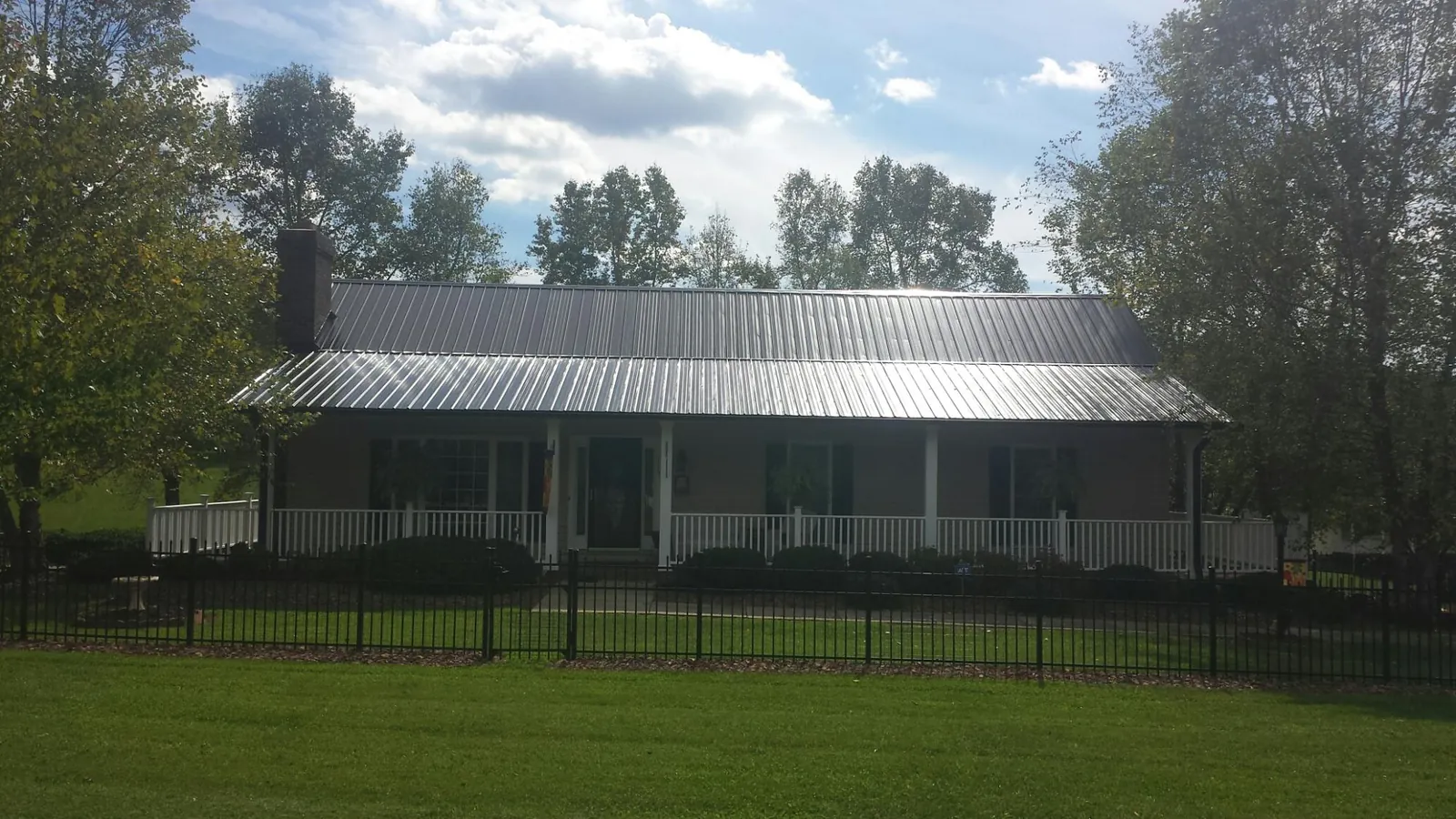 Gray metal roof on a brick ranch with a full width front porch — Gutter Guard Installation work by our crew in Keithsburg