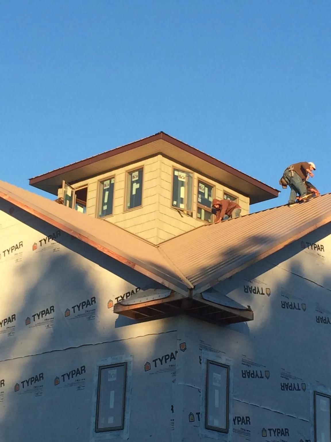 Roofers working around a rooftop cupola on a new metal roof at sunset — Roof Waterproofing in Keithsburg by Roofing Brothers